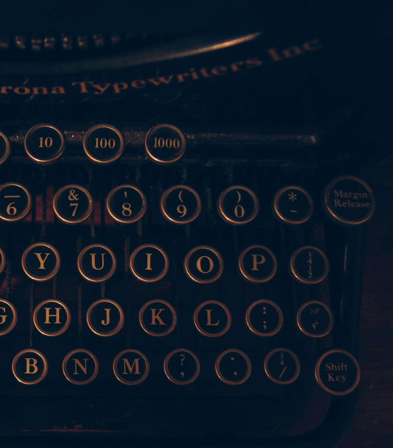 a black typewriter with gold embossed keys (for Support Sorcery, providing business support and strategic sorcery for magicians and witches in business)